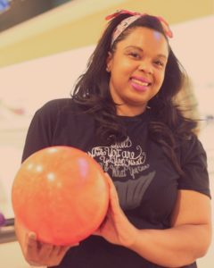smiling woman holding a pink bowling ball