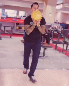 man in bowling pose holding a ball in hand
